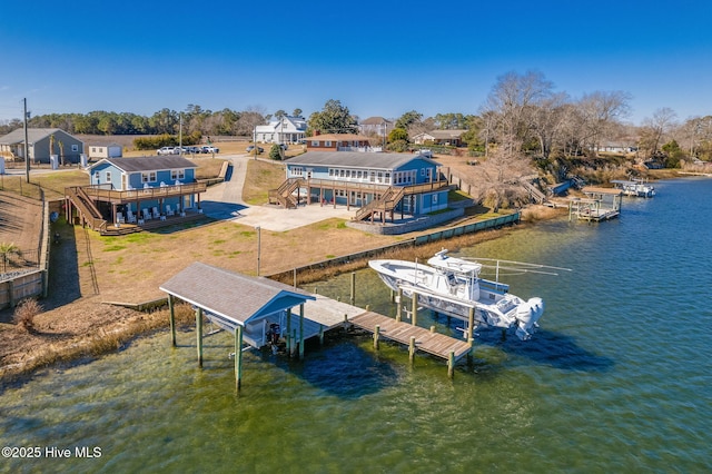 dock area featuring a patio, boat lift, a deck with water view, stairs, and a yard