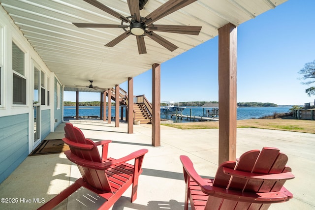 view of patio featuring a water view, ceiling fan, and stairway