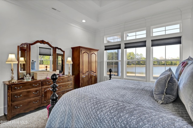 bedroom with a water view, multiple windows, visible vents, and crown molding