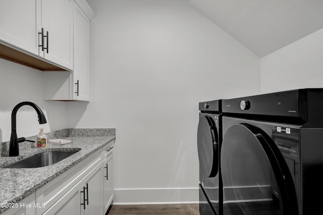 laundry room with washer and clothes dryer, cabinet space, dark wood-type flooring, a sink, and baseboards