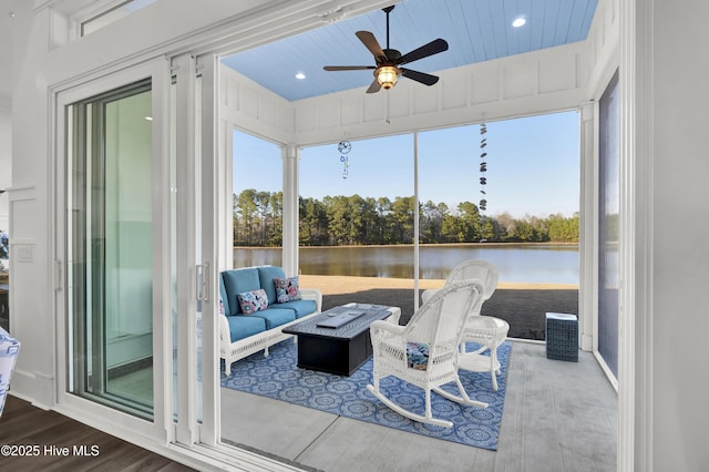 sunroom / solarium with ceiling fan and a water view