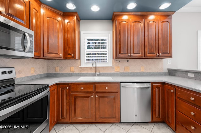 kitchen with light countertops, appliances with stainless steel finishes, a sink, and brown cabinets