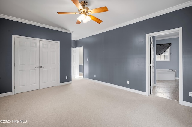 unfurnished bedroom featuring light carpet, ornamental molding, a closet, and baseboards