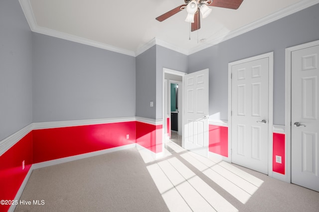 unfurnished bedroom featuring carpet, crown molding, baseboards, and ceiling fan