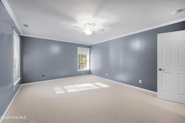 unfurnished room featuring ceiling fan, light colored carpet, visible vents, baseboards, and crown molding