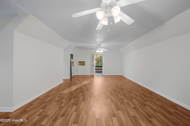 unfurnished living room featuring lofted ceiling, ceiling fan, baseboards, and wood finished floors