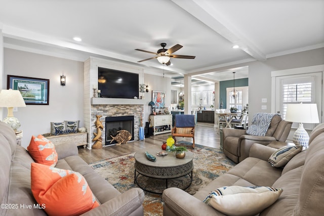 living area featuring recessed lighting, beam ceiling, a stone fireplace, and wood finished floors