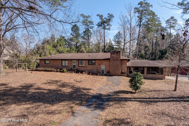 ranch-style house with brick siding, driveway, and a chimney