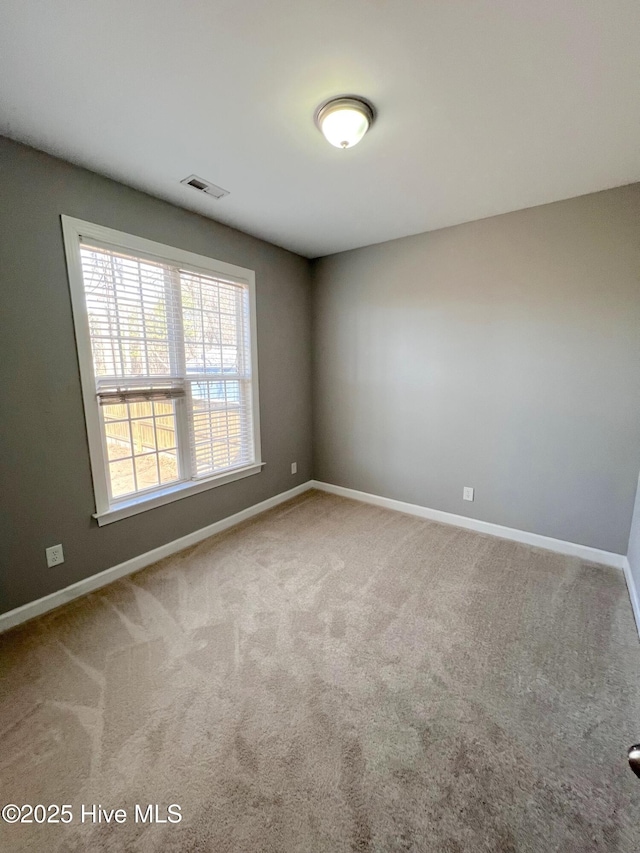 spare room with carpet, baseboards, and visible vents