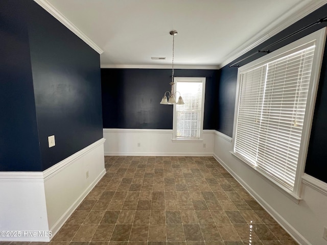 unfurnished dining area with ornamental molding, a wainscoted wall, and an inviting chandelier