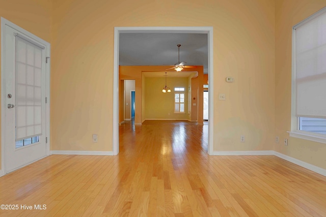 empty room with ceiling fan, baseboards, and light wood-type flooring