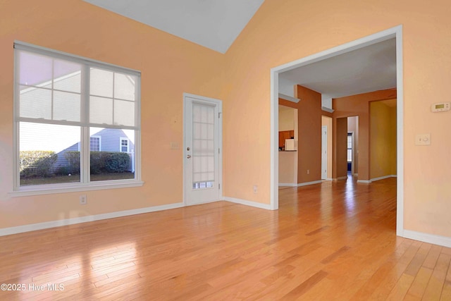 unfurnished room with baseboards, lofted ceiling, and light wood-type flooring