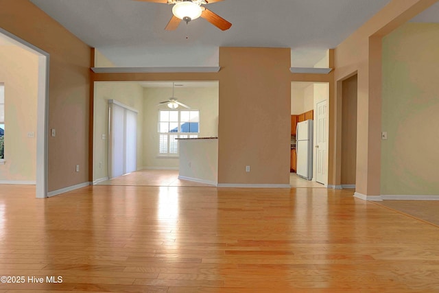 unfurnished living room featuring light wood-style floors, a ceiling fan, and baseboards