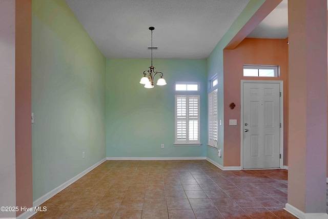 tiled foyer entrance with a chandelier, visible vents, and baseboards