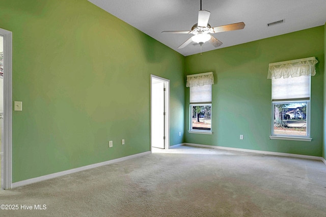 carpeted empty room with baseboards, a ceiling fan, and visible vents