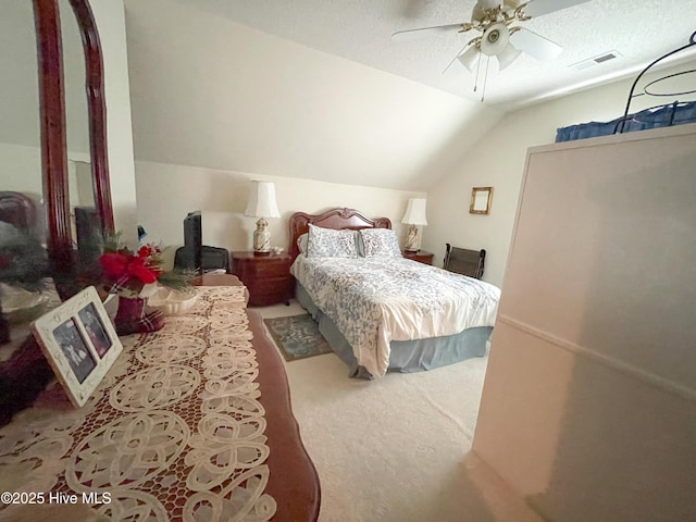 bedroom with lofted ceiling, carpet floors, visible vents, and a textured ceiling