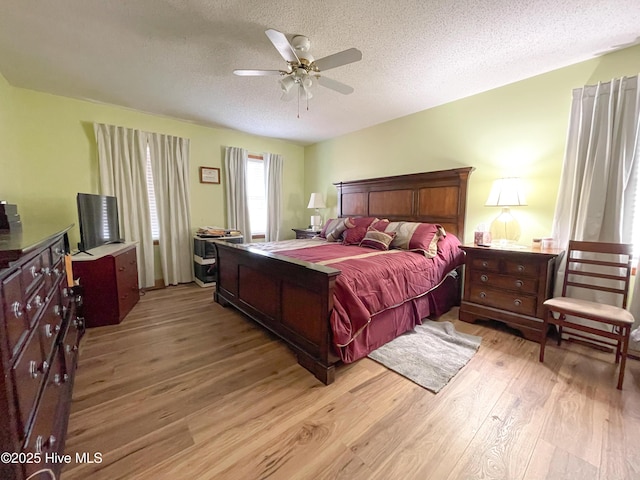 bedroom with a textured ceiling, ceiling fan, and light wood-style floors