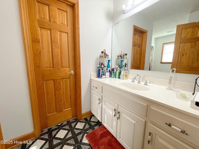 bathroom with walk in shower, vanity, and baseboards