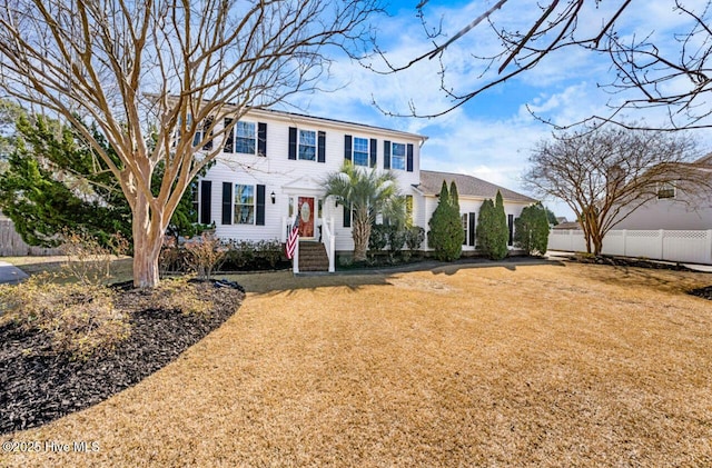 colonial-style house with a front lawn and fence