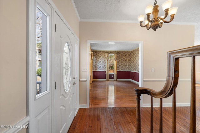 entrance foyer with a textured ceiling, hardwood / wood-style flooring, baseboards, wallpapered walls, and crown molding