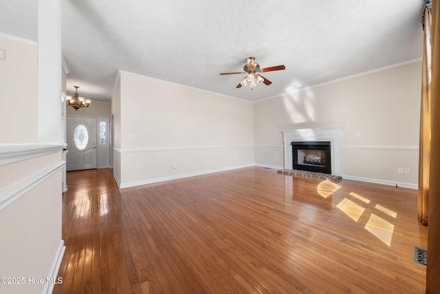 unfurnished living room featuring wood-type flooring, a fireplace with raised hearth, crown molding, and baseboards