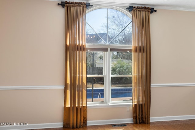 doorway with visible vents, plenty of natural light, baseboards, and wood finished floors