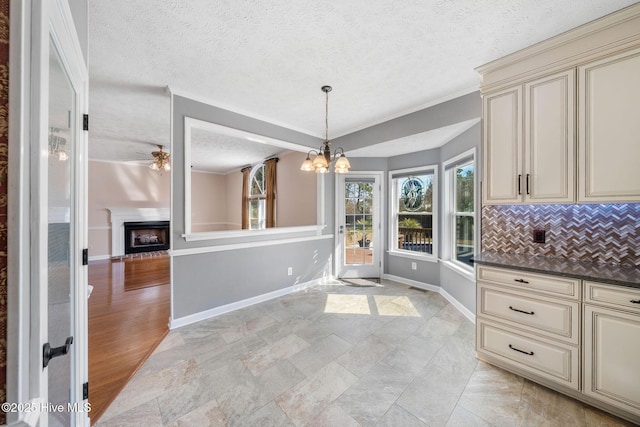 kitchen with cream cabinetry, baseboards, a fireplace, and decorative backsplash