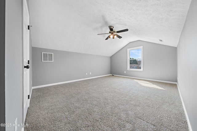 additional living space featuring lofted ceiling, a textured ceiling, visible vents, baseboards, and carpet