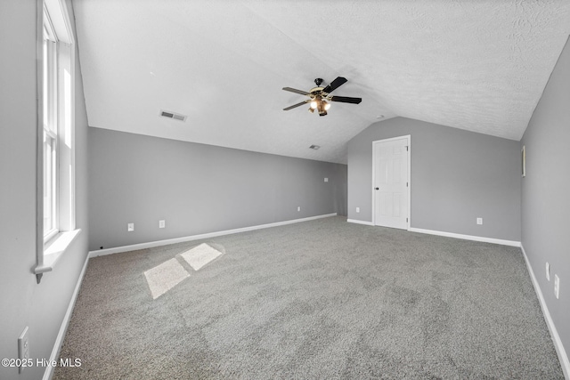 bonus room with a textured ceiling, vaulted ceiling, carpet flooring, and visible vents