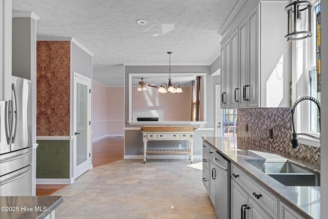 kitchen with appliances with stainless steel finishes, crown molding, a sink, and a textured ceiling