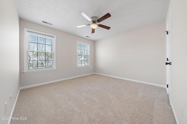 carpeted empty room with a textured ceiling, ceiling fan, visible vents, and baseboards