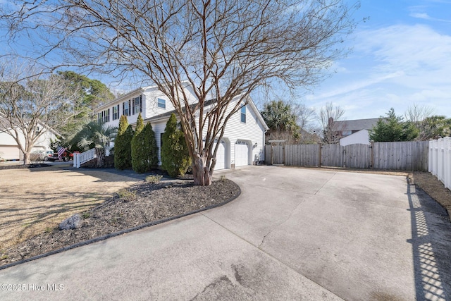 view of side of property featuring concrete driveway, fence, and a gate