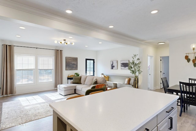 kitchen with light wood finished floors, light countertops, crown molding, and a center island