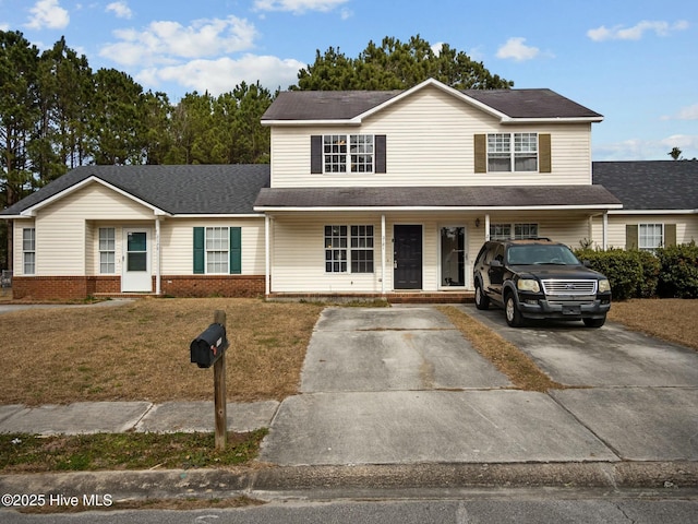 view of front facade with covered porch, brick siding, driveway, and a front lawn