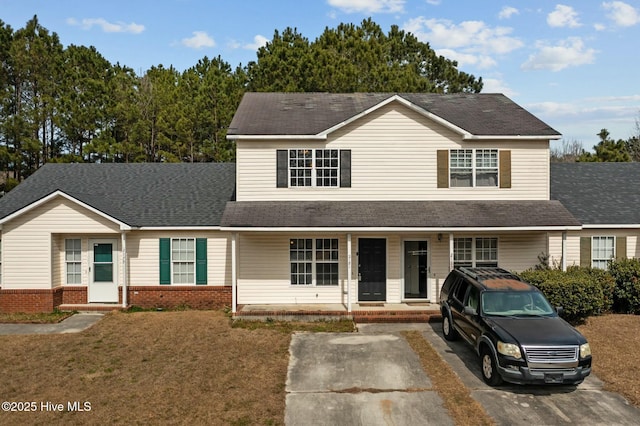 view of front of home featuring covered porch, brick siding, roof with shingles, and a front lawn