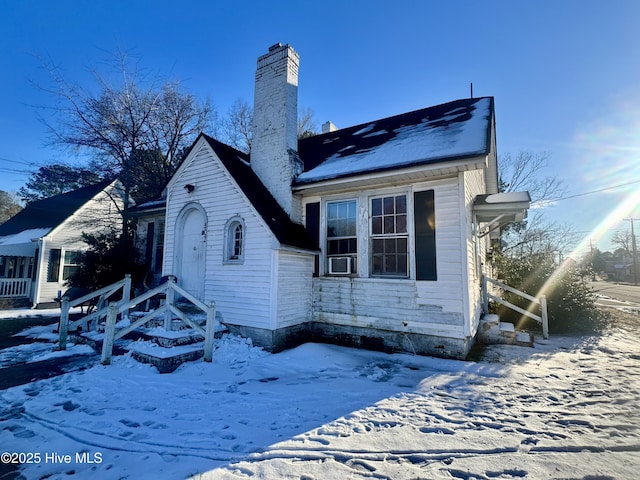 view of snow covered exterior featuring a chimney and cooling unit