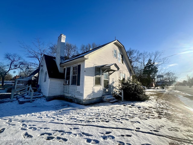 view of snow covered exterior featuring entry steps and a chimney