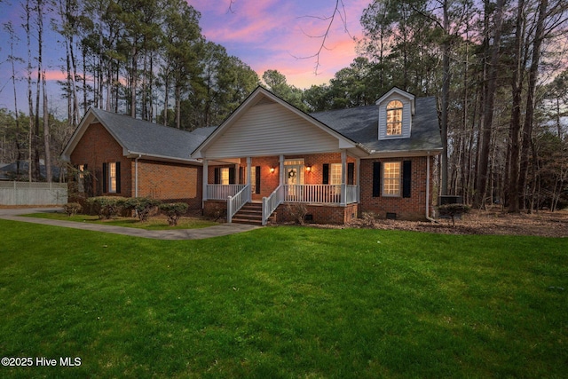 view of front of home with covered porch, brick siding, crawl space, and a lawn