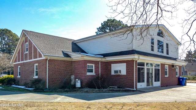 view of front of property featuring roof with shingles, cooling unit, and brick siding