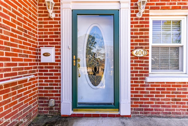 view of exterior entry featuring brick siding