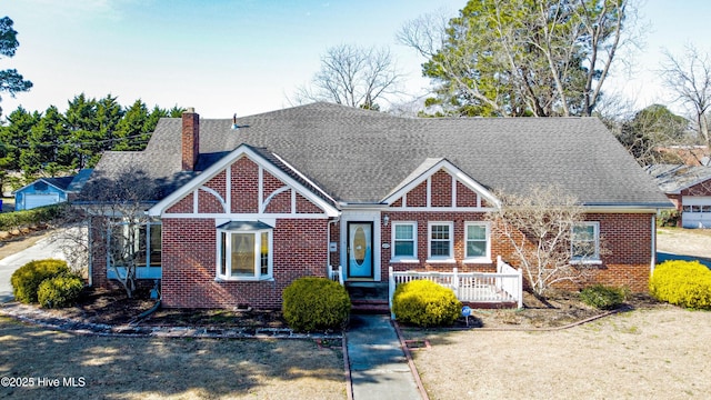 view of front facade with brick siding, a chimney, a front lawn, and roof with shingles