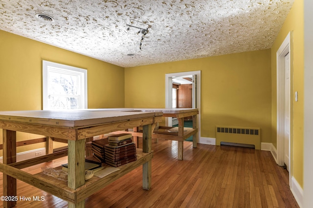 playroom featuring baseboards, visible vents, radiator heating unit, and hardwood / wood-style flooring