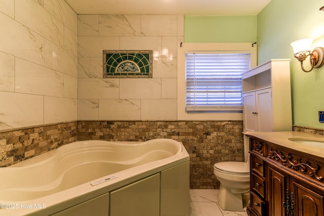 full bathroom featuring marble finish floor, a garden tub, tile walls, toilet, and vanity