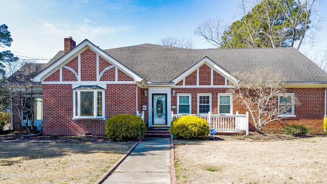 view of front of property with brick siding, a chimney, and a shingled roof