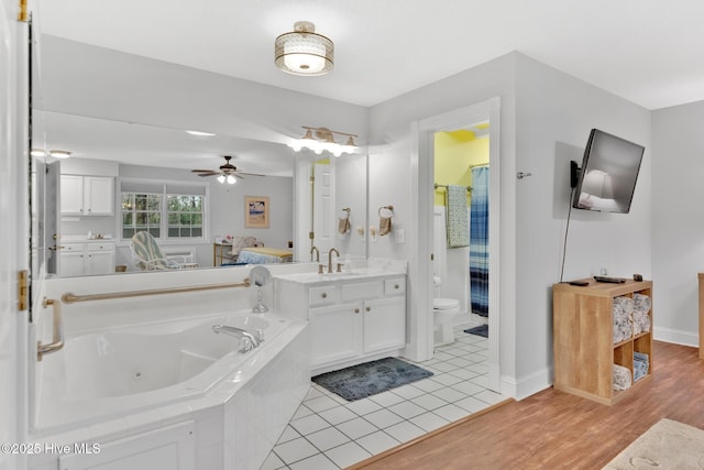 full bath with a ceiling fan, toilet, wood finished floors, a jetted tub, and vanity