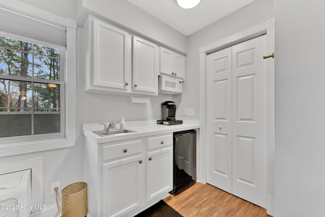 kitchen with white microwave, refrigerator, a sink, white cabinetry, and light countertops