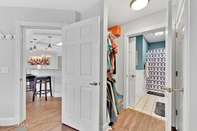 bathroom with a shower with shower curtain, wood finished floors, and an inviting chandelier