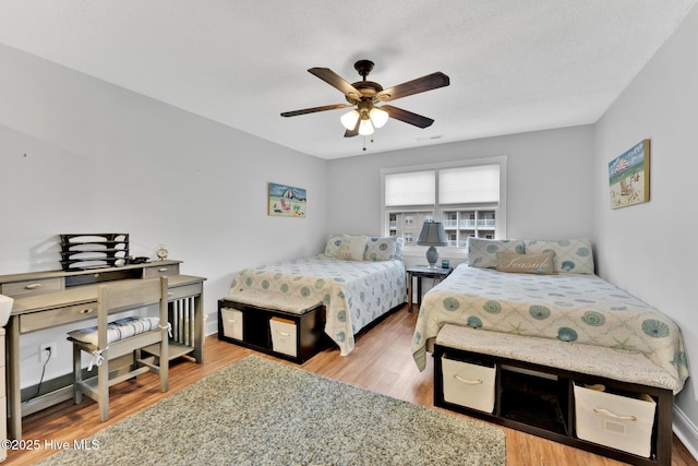 bedroom featuring baseboards, a ceiling fan, wood finished floors, and visible vents