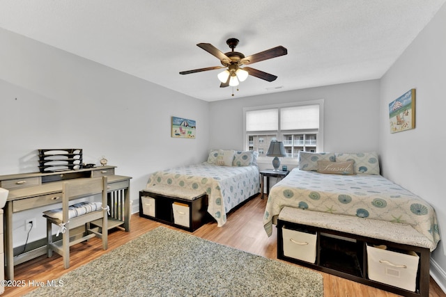 bedroom featuring a ceiling fan, visible vents, baseboards, and wood finished floors