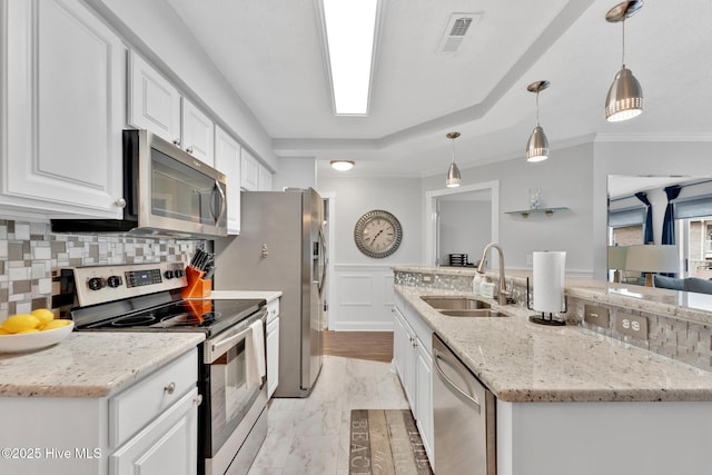 kitchen featuring visible vents, white cabinets, a wainscoted wall, stainless steel appliances, and a sink